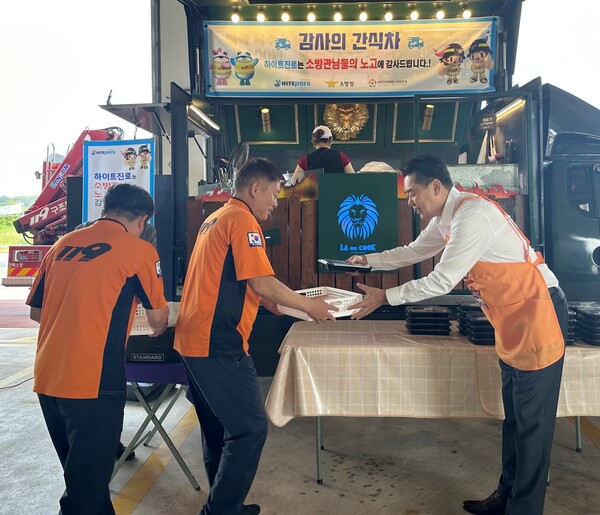 지난 12일 김인규 하이트진로 대표(오른쪽)가 완주소방서 소방공무원에게 간식을 직접 전달하고 있다. 사진=하이트진로 제공